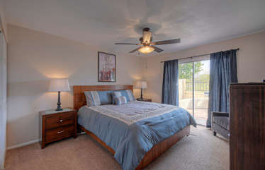 Primary bedroom with king bed, TV and ceiling fan has large closet and sliding doors to private patio