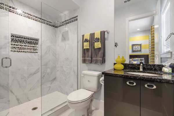 The ensuite bathroom perfectly matches the bedroom with pops of grey and yellow
