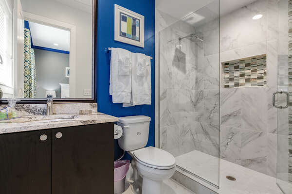 This bathroom is complete with a glass walk-in shower and granite countertops