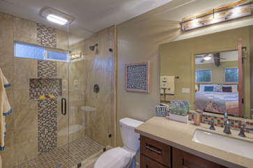 West primary suite bath features a modern tile and glass walk-in shower.