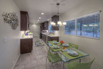 The modern kitchen includes an eating area with natural light from windows.