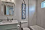 Wall-hanging hangs above toilet in a private bathroom beside a vanity sink and shower.