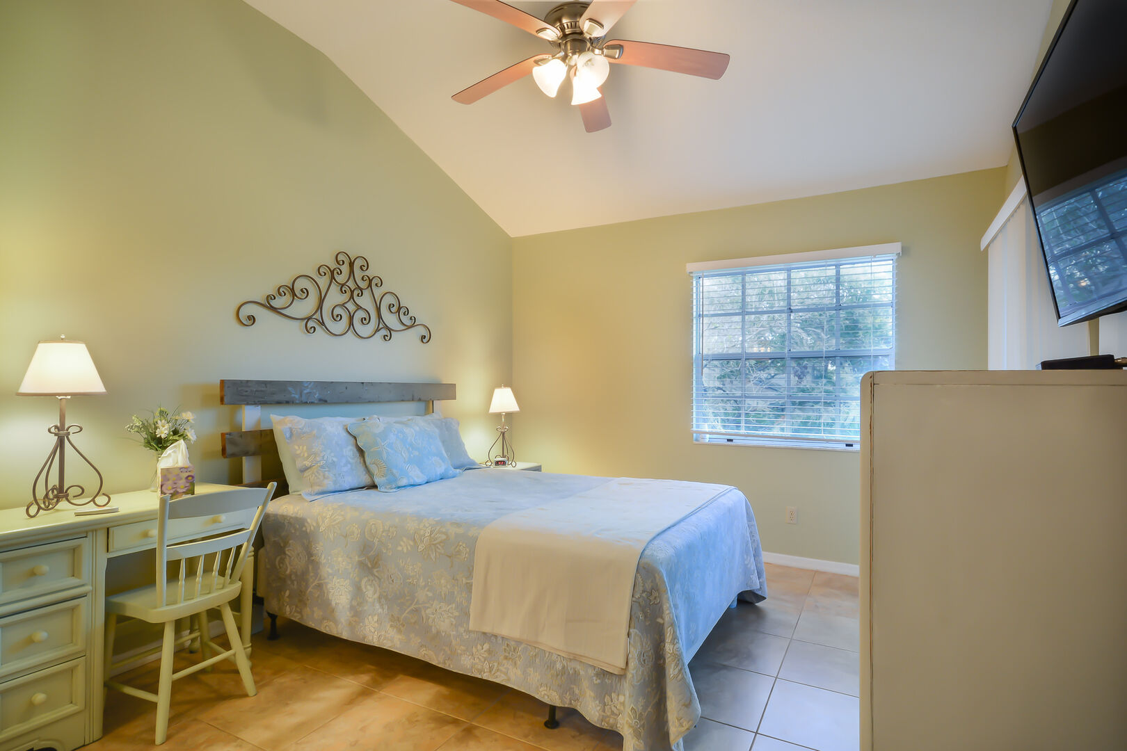 Master bedroom of this vacation rental in New Smyrna Beach FL with a queen-sized bed, large flat-screen TV, and Desk area.