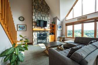 The Living Area Features Large Picturesque Windows and a Stone Fireplace