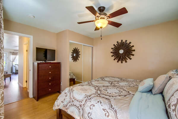 Bedroom with Closet, Large Bed, Dresser, TV, and Ceiling Fan.