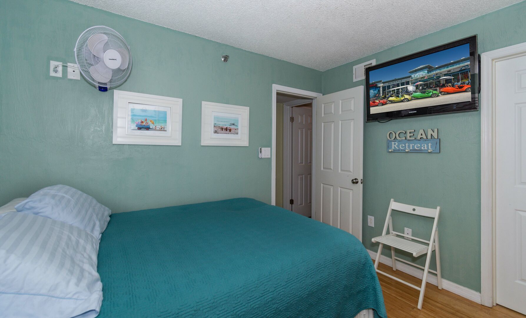 Guest bedroom with a flat-screen TV, large bed, and wall-mounted fan.
