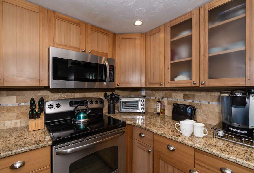 Keurig coffee maker, toaster oven, and toaster in the kitchen next to the oven range and microwave.