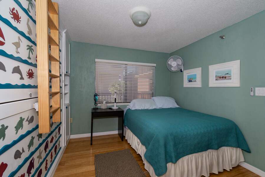 The guest bedroom of this vacation condo in New Smyrna Beach with a full-sized bed and bunk bed.