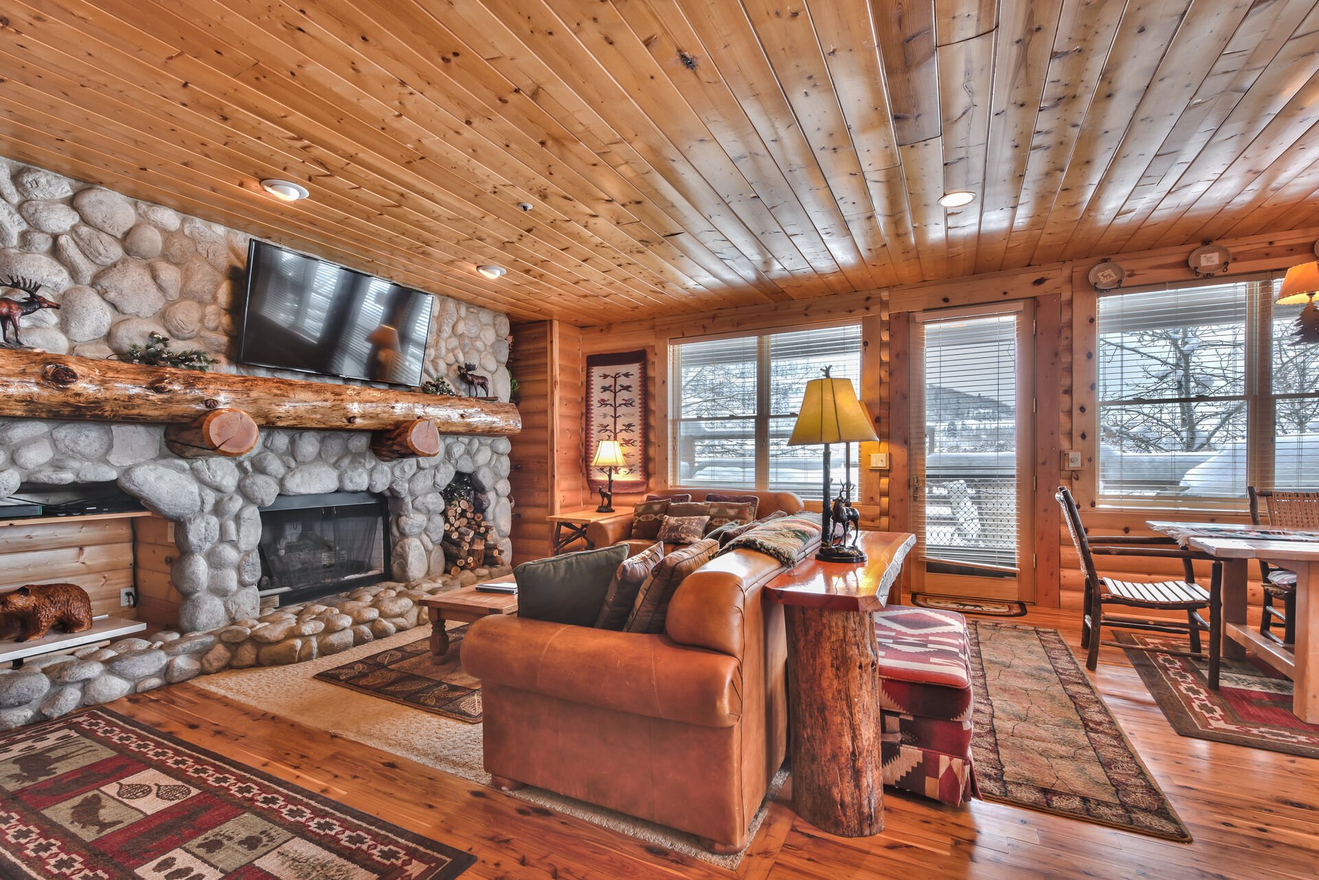 Living Room with Comfortable Mountain Furnishings, a Queen Sleeper Sofa, Stone Fireplace, Flat Screen TV, and Private Deck with Mountain Views