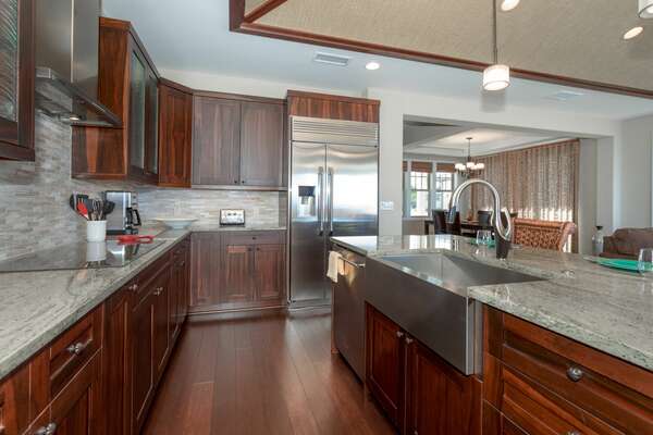 Fully Equipped Kitchen of this Kona Hawaii vacation rental with large fridge, island with sink, and countertop range.