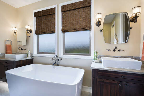 Master Bathroom with large tub flanked by two vanity sinks.