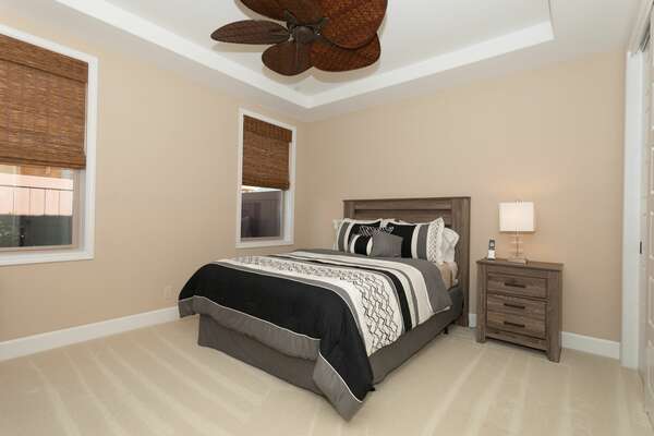 Ornate ceiling fan, nightstand, and large bed in bedroom 2.