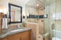 The bathroom is adorned with natural stone tile work, glass & custom wood cabinetry.