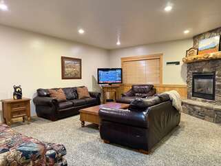 Basement living room with fireplace, seating, and television.