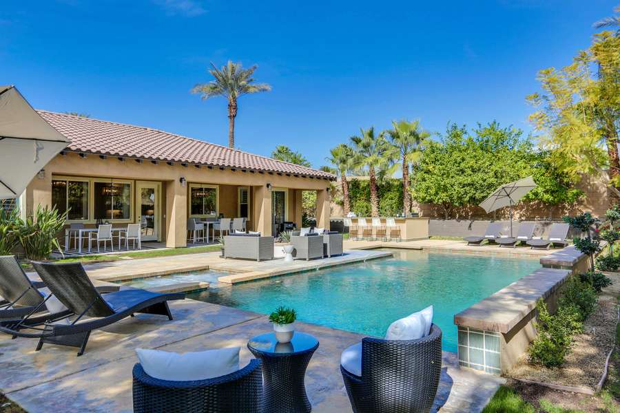 Impressive backyard with resort-style amenities such as comfortable chaise lounge seating for 6, outdoor fire pit, al fresco dining for 12 and built in BBQ with mini fridge