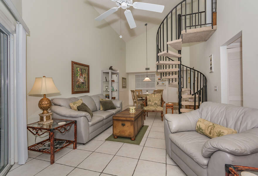 The living room of this Vacation Rental at New Smyrna Beach with a spiral staircase in the background.