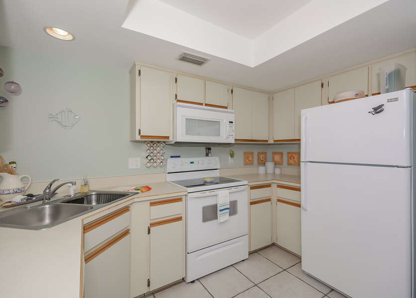 The bright open kitchen of this Vacation Rental at New Smyrna Beach with fridge, oven range, and microwave.