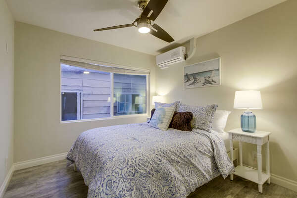 Bedroom with Large Bed, Nightstands, Lamps, AC, and Ceiling Fan.