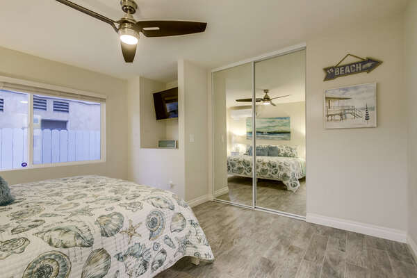 Bedroom with Large Bed, TV, Ceiling Fan, and Mirror Closet Doors.