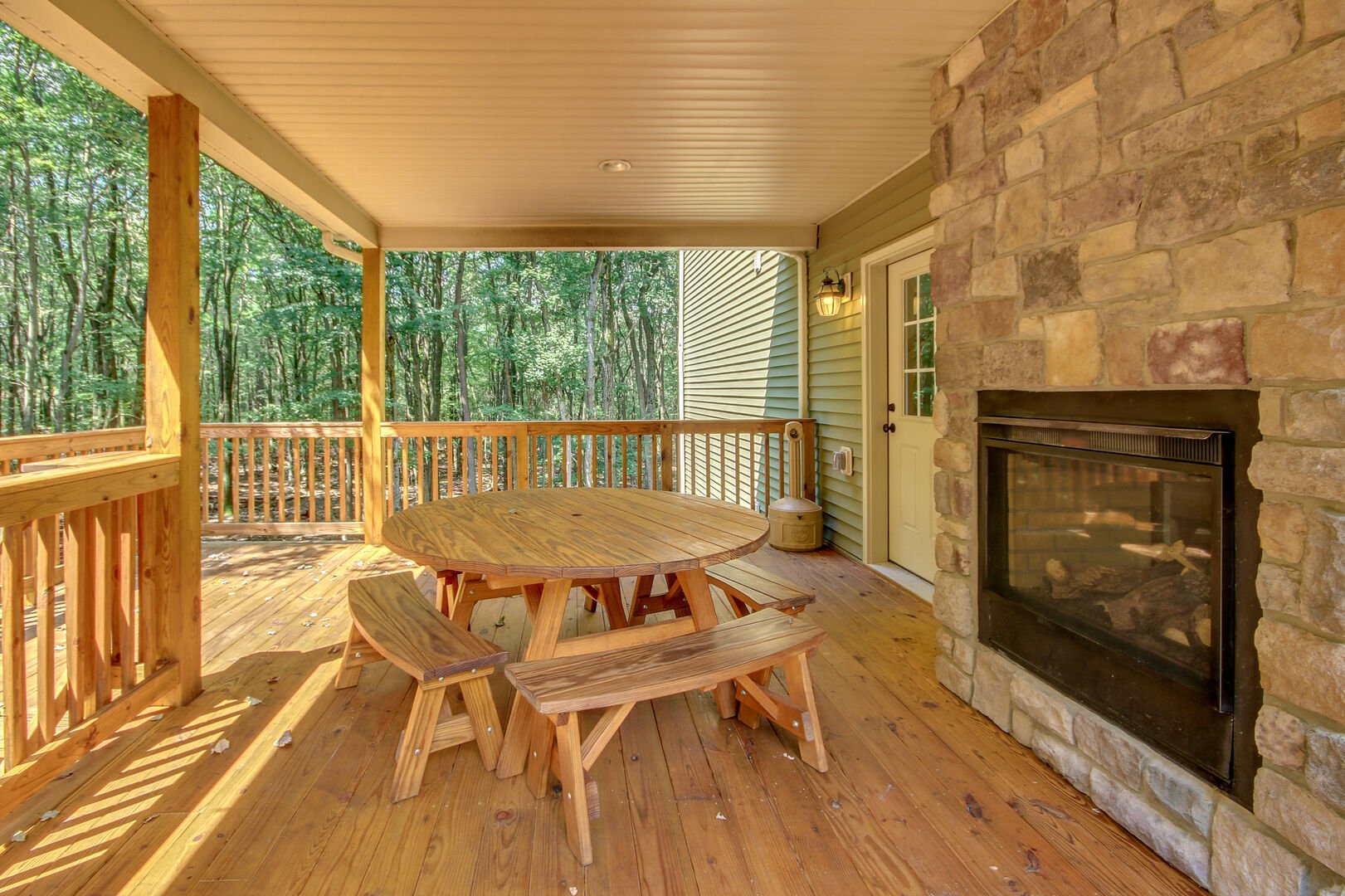 The outdoor fireplace located on the porch, next to a round picnic table.