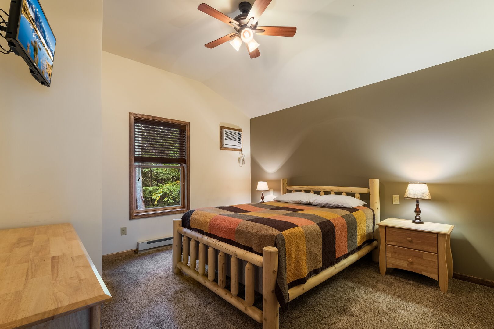 Large bed, nightstands, dresser, and TV of a room in this luxurious Poconos vacation rental.