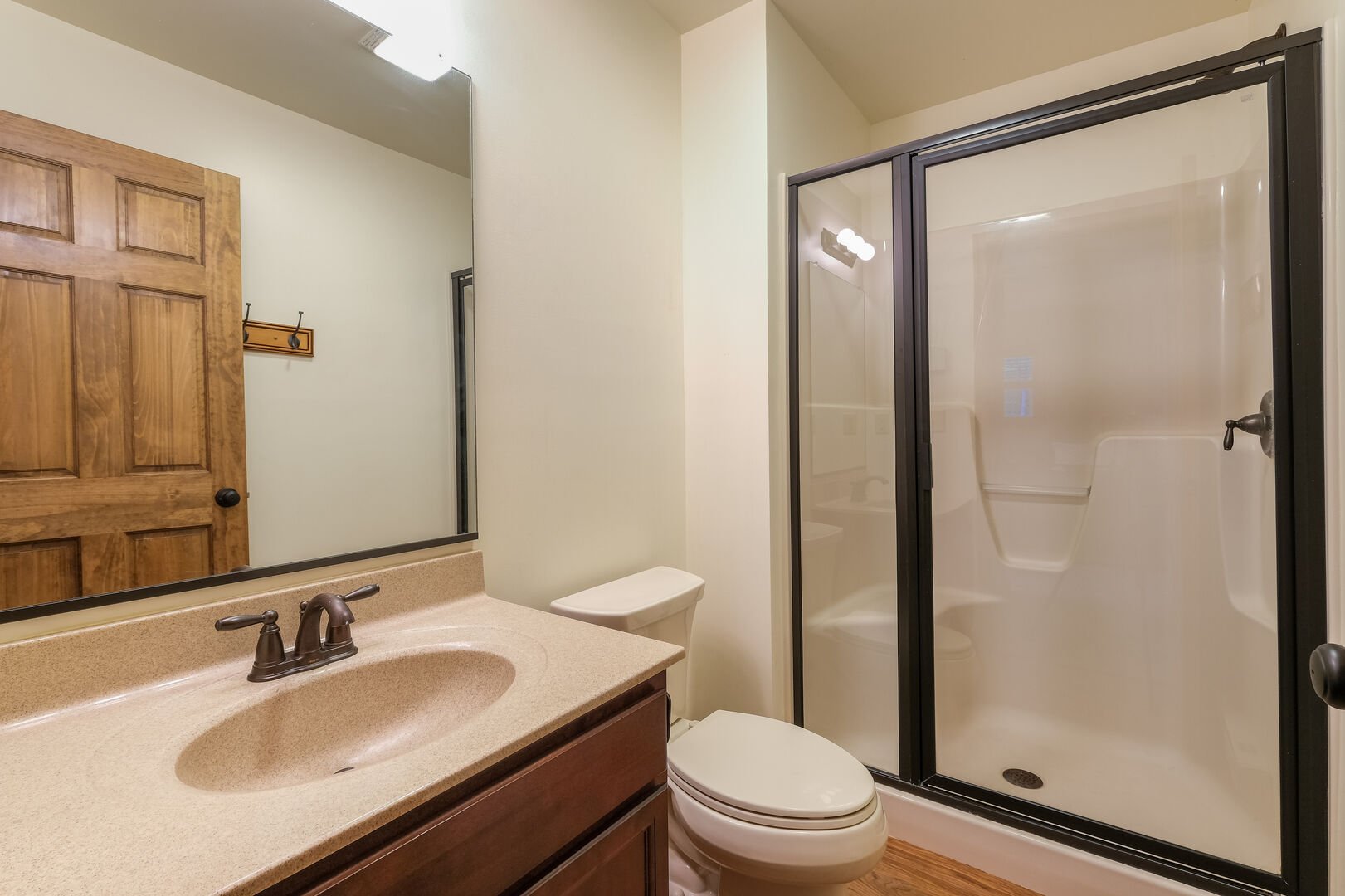 Bathroom with toilet, sink and mirror, and walk in shower with glass door,