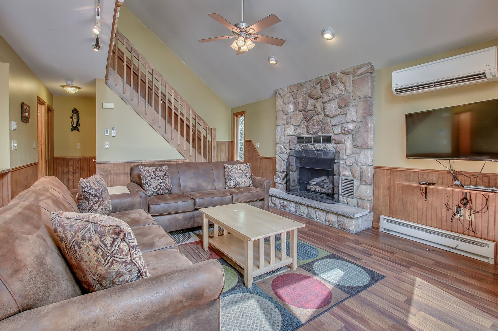 The great room of this Pocono rental in Towamensing Trails, with two couches, a fireplace, a coffee table, and TV.