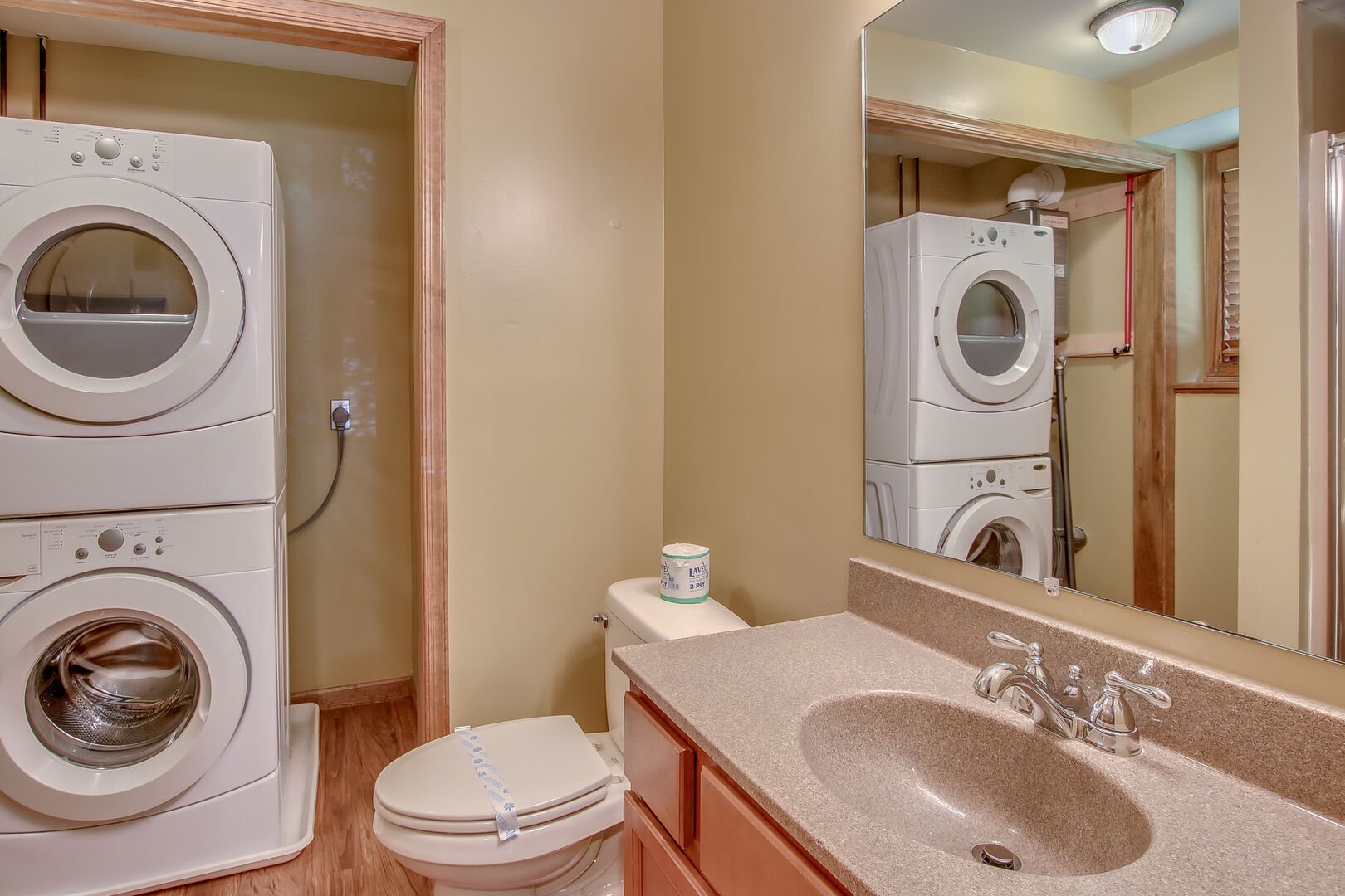 Bathroom with a sink and mirror, toilet, washer and dryer.