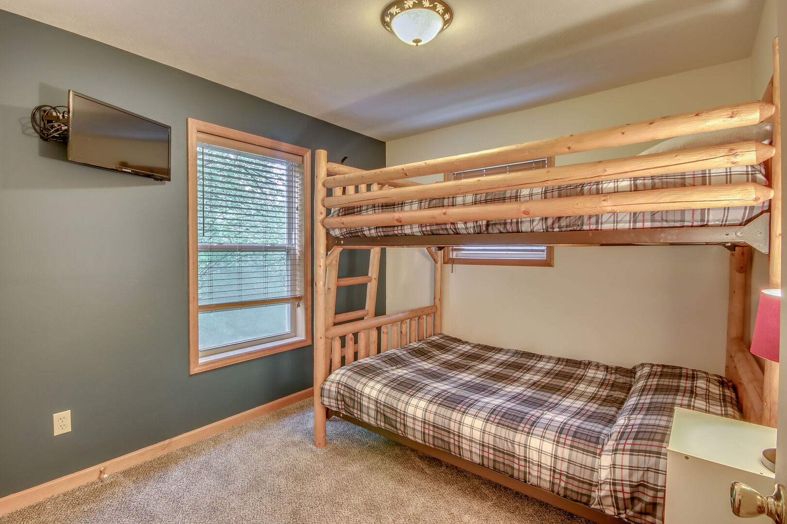 An Image of a Wooden Bunk Bed  and TV on the Wall of Bedroom.