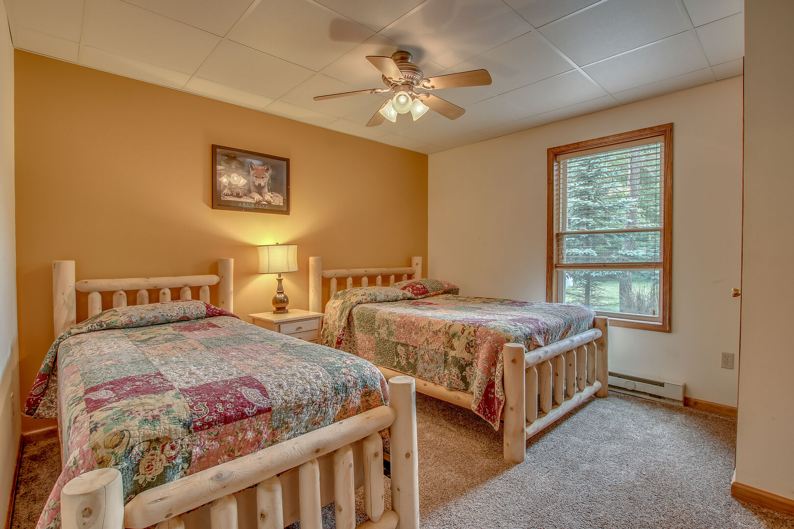 tan bedroom with two beds beneath ceiling fan
