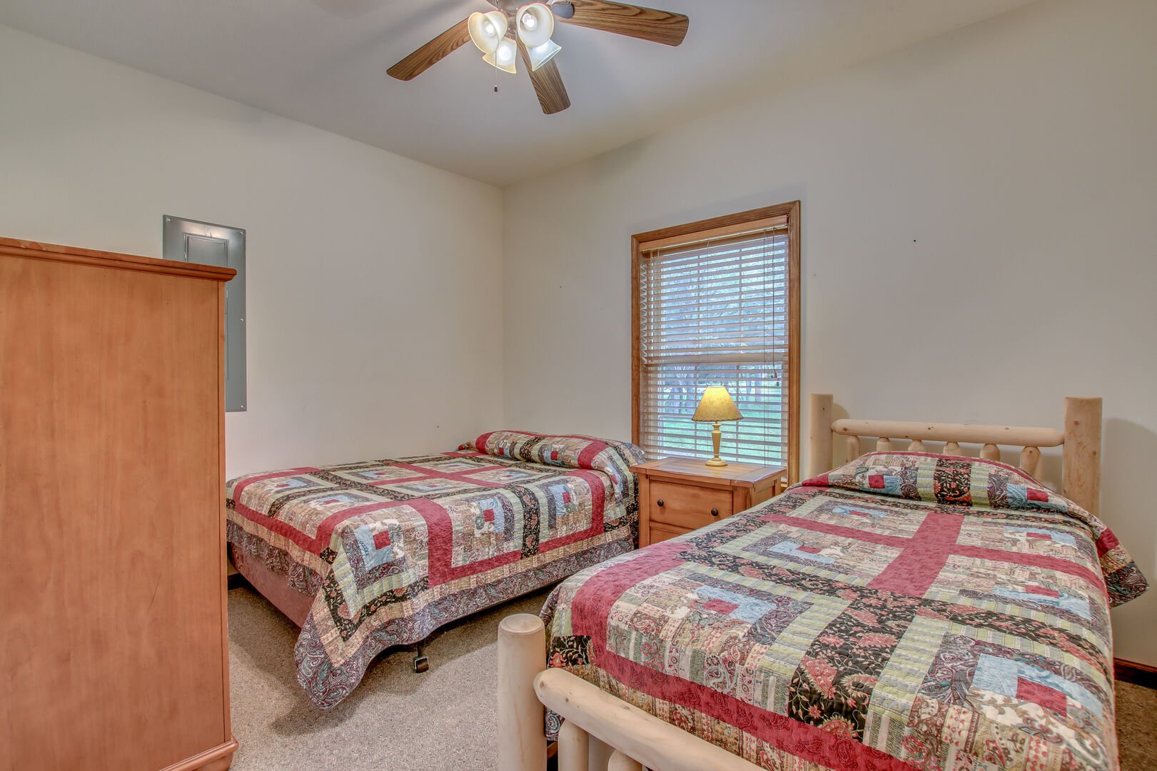 Bedroom with Two Beds, Nightstand, Table Lamp, Dresser, and Ceiling Fan.