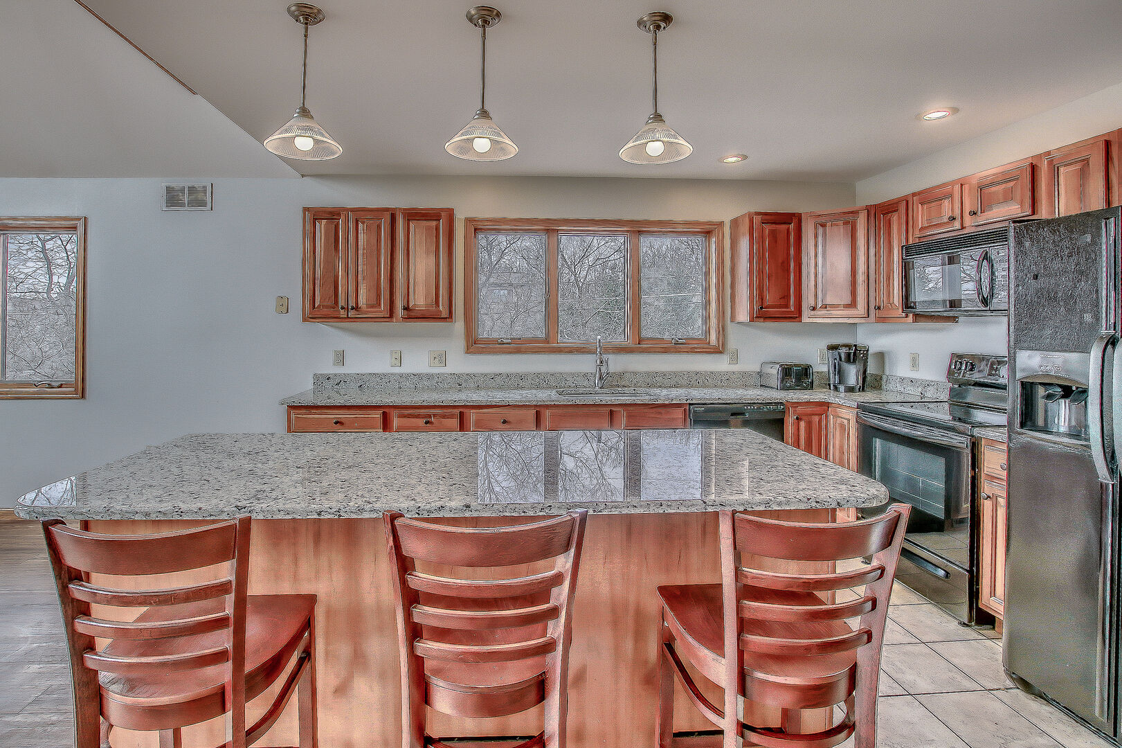 Spacious Kitchen Features Island, Chairs, and Refrigerator.