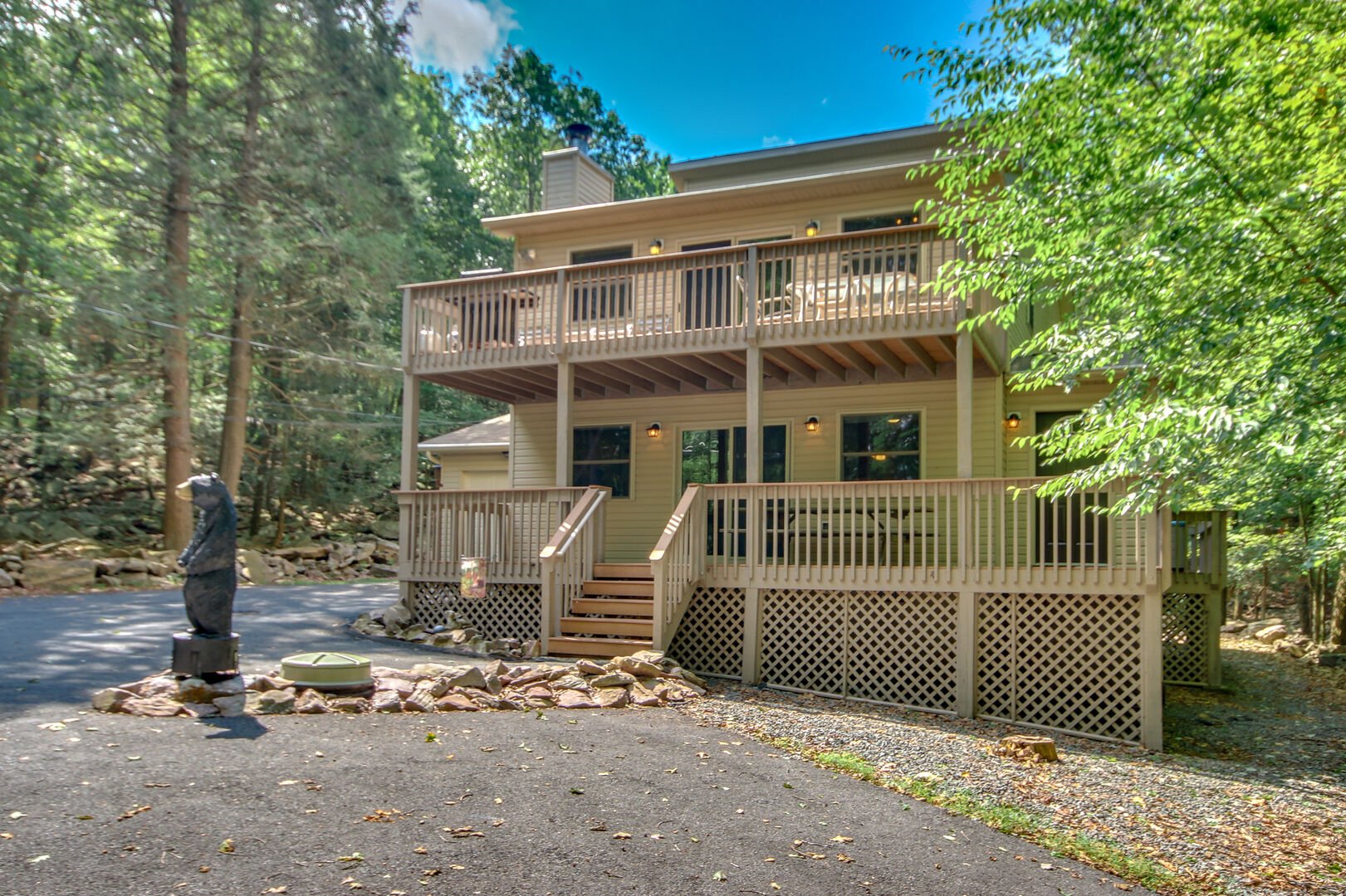The exterior of this Lake Harmony rental, with its two patios and a bear statue out front.