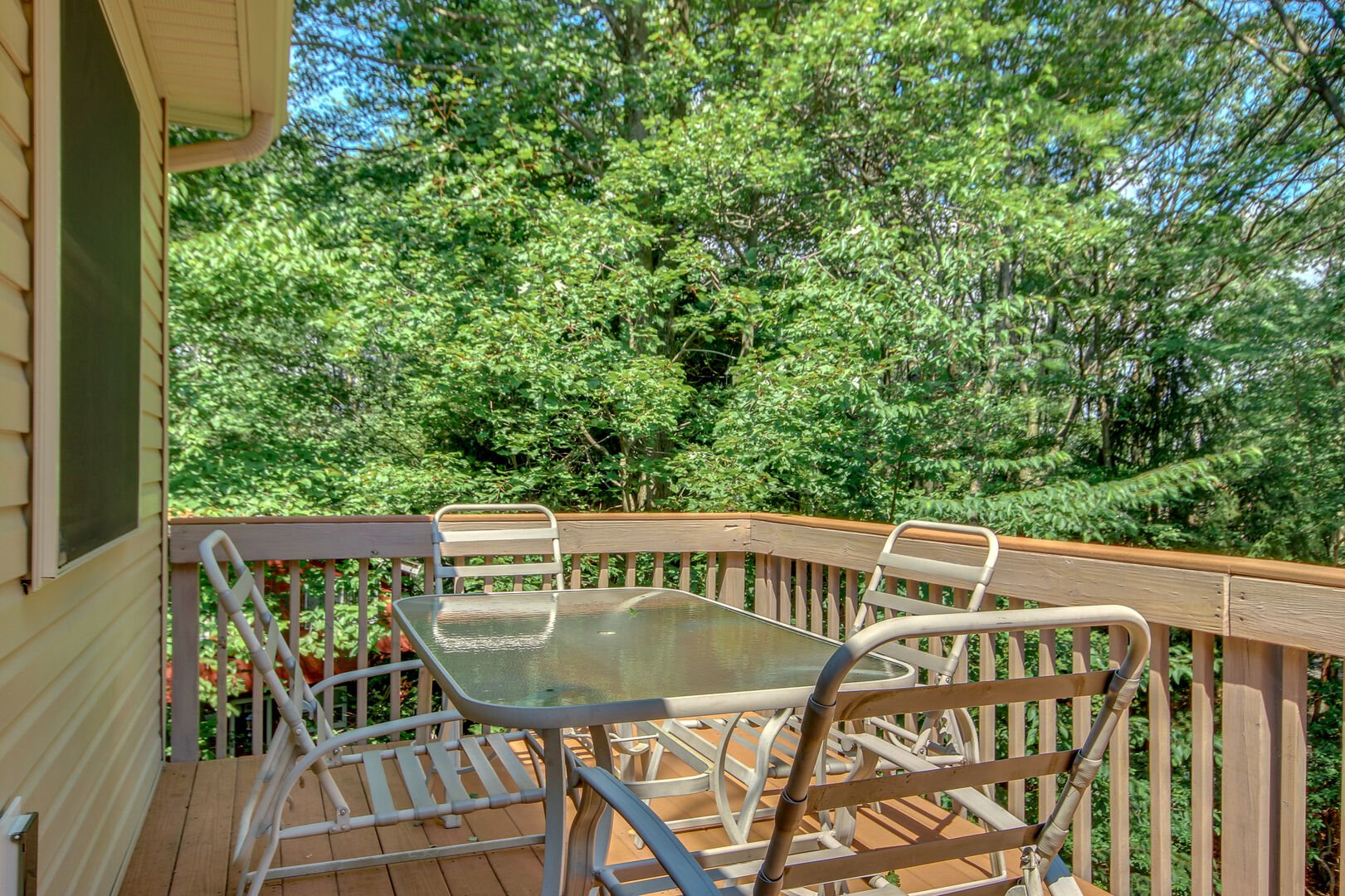 The upper balcony of this Lake Harmony rental, with a glass table and 4 outdoor chairs.