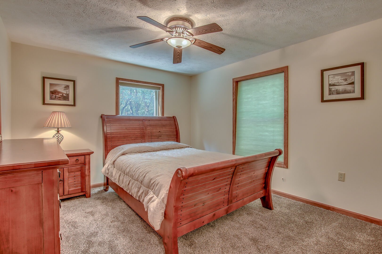 Bed in the center of a bedroom, with a nightstand and dresser to the right, a window to the left.
