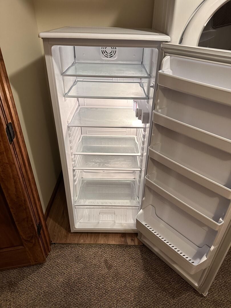 Dorm Size Fridge in Laundry Room, Perfect for Storing Drinks and Snacks.