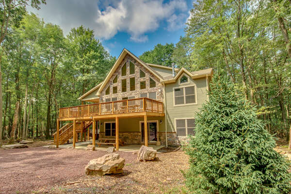 Angled photo of the exterior of this luxurious Poconos vacation rental, with view of elevated porch.