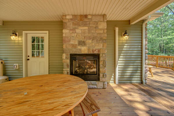 The picnic table and outdoor fireplace located on the porch.