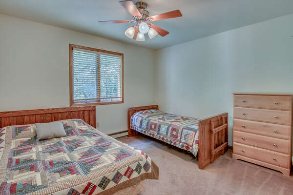 A bedroom with a bed on the left wall, a smaller bed and dresser on another.