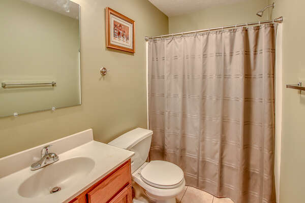 A picture of one of this Lake Harmony rentals bathrooms, with a toilet, sink, mirror, and shower in shot.