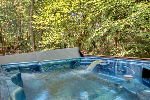 A picture of the hot tub, filled with water, and a view of the forest beyond.