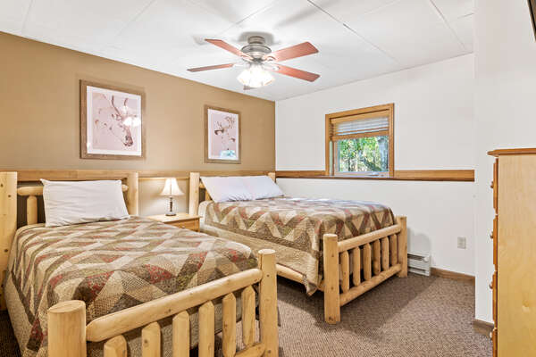 tan bedroom with two beds and ceiling fan