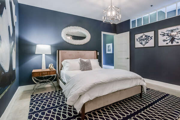 Bedroom with Large Bed, Nightstand, Table Lamp, and Mirror.