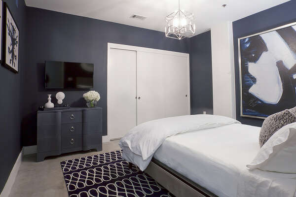 Bedroom with Large Bed, TV, Dresser, and Closet.