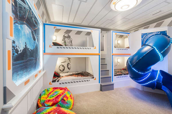 A fun kids room featuring custom built bunk beds with a slide