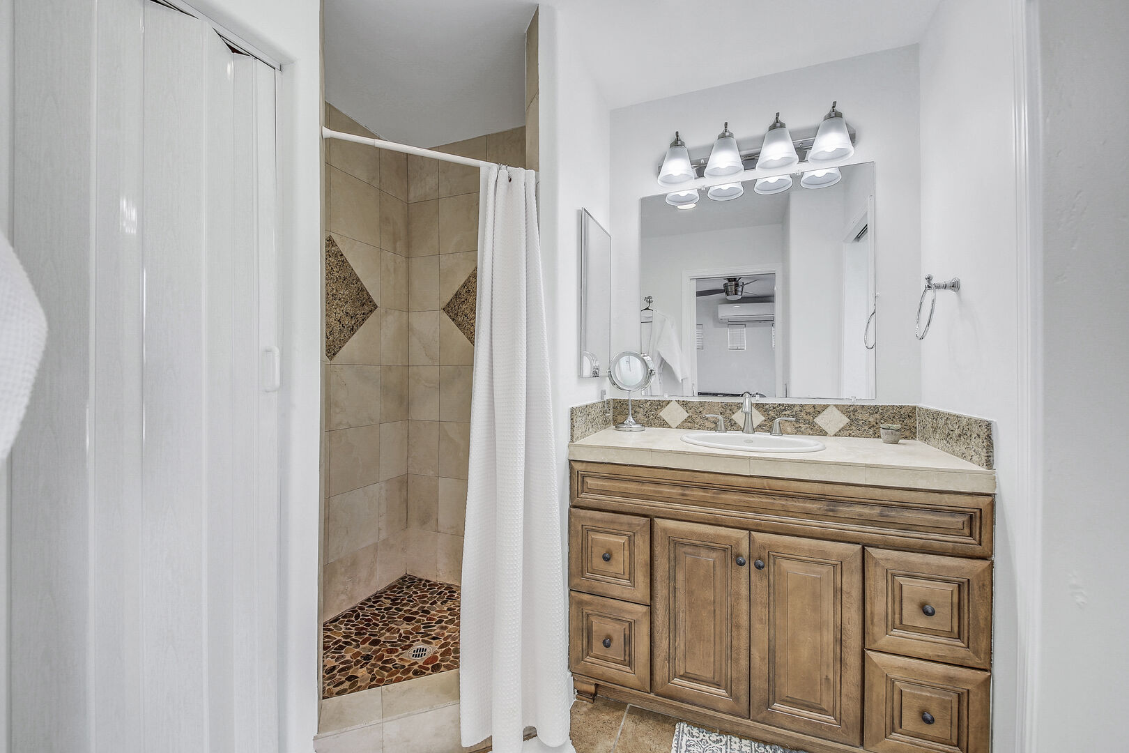 The private, en suite bathroom features a tile shower, and a vanity sink.