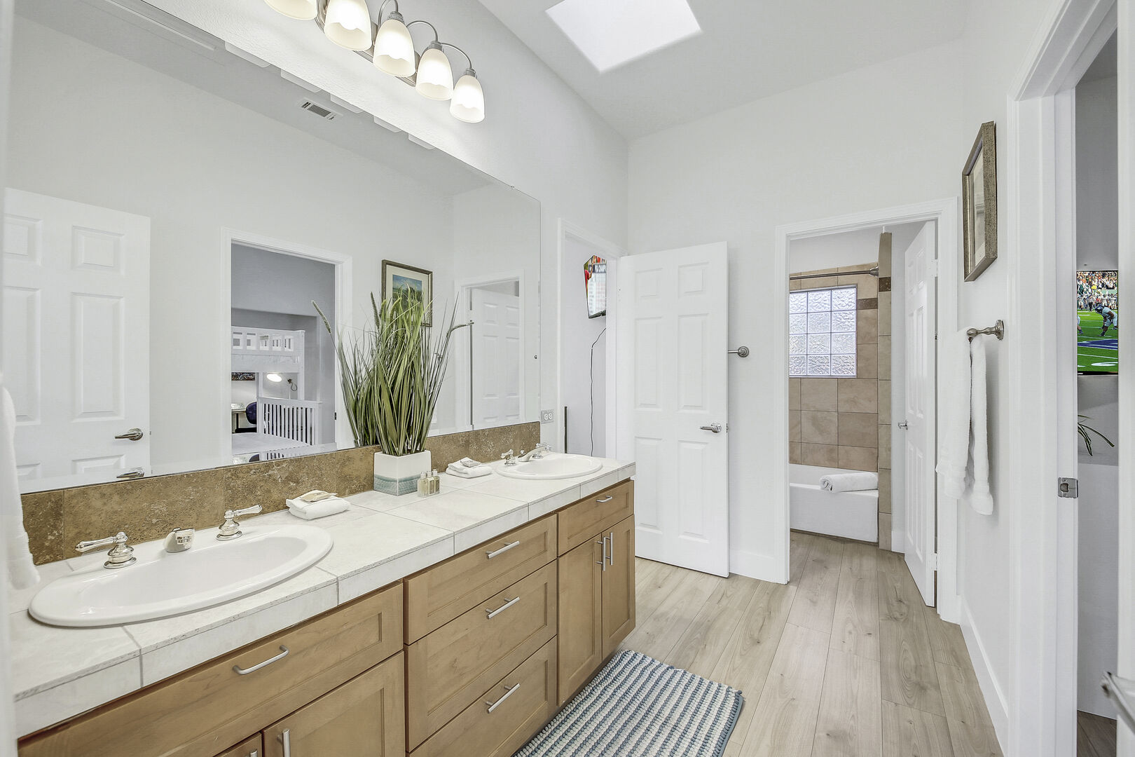 Shared, jack and jill bathroom features a shower and tub combo, and double vanity sinks.