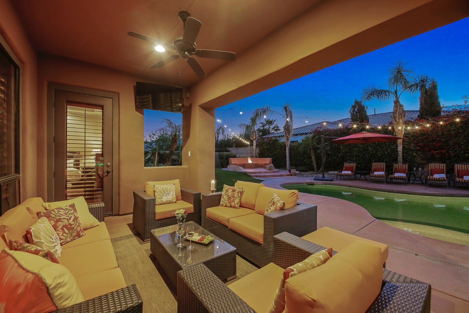 Covered outdoor living area with TV and seating for seven.
