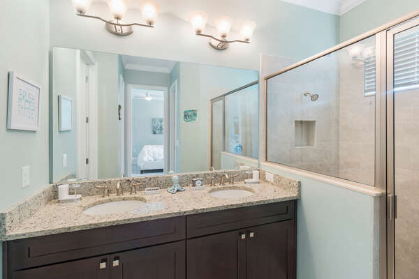 The ensuite master bathroom features a walk-in shower and his and hers sinks