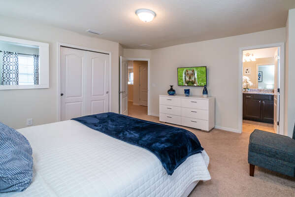 Master bedroom upstairs showing king bed, TV and bath access